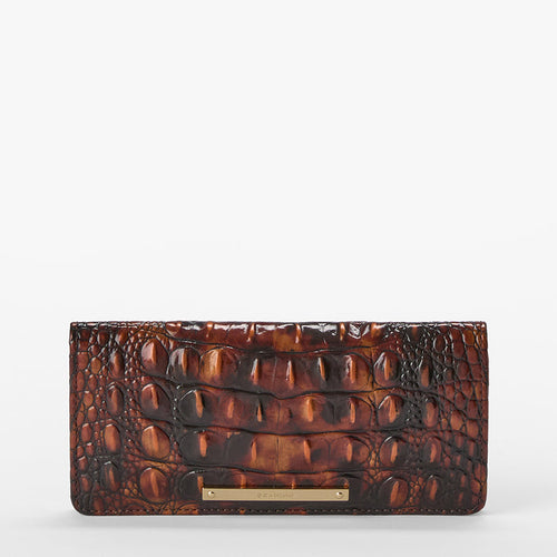 A brown crocodile-embossed leather clutch wallet with a gold-tone Brahmin bar detail at the bottom, shown against a plain white background.