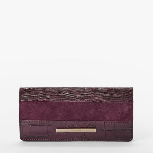 A rectangular wallet in deep purple, featuring a textured woven top section, a suede-like middle band, an embossed crocodile pattern bottom, and a gold-tone Brahmin plaque.