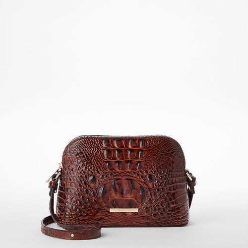 An upright Amal crossbody bag, crafted from brown croc-embossed leather with a gold plate on the front and an adjustable strap, set against a white background.
