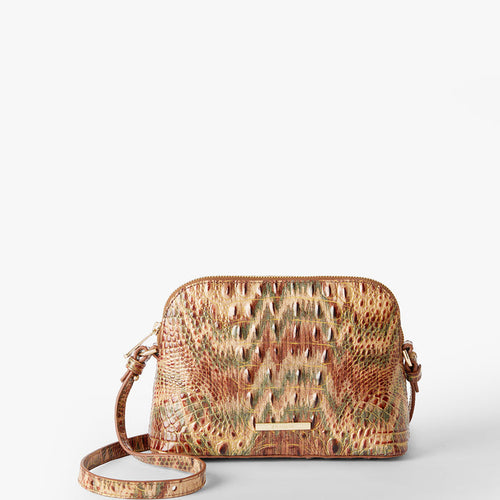 A small dome-shaped crossbody bag with a textured crocodile skin pattern in shades of brown, beige, and muted green, featuring a gold Brahmin plaque on the front. Amal Front View.
