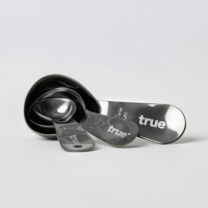 True brand set of four stainless steel nested measuring spoons with engraved sizes and logo on white background, product kitchen utensil photo