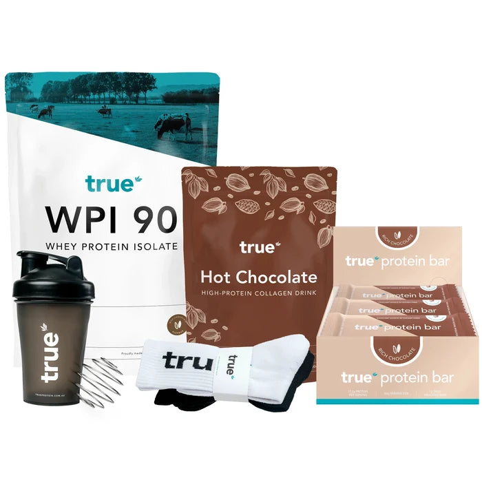 True protein starter bundle: True WPI 90 whey protein isolate bag, True Hot Chocolate high‑protein collagen drink pouch, box of True protein bars (Rich Chocolate), black True shaker bottle with mixing whisk and branded socks on white background