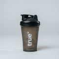 True Protein small black plastic protein shaker bottle with flip lid and visible mixing mechanism, product studio photo on white background — TrueProtein (Australia)