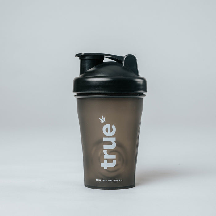 True Protein small black plastic protein shaker bottle with flip lid and visible mixing mechanism, product studio photo on white background — TrueProtein (Australia)