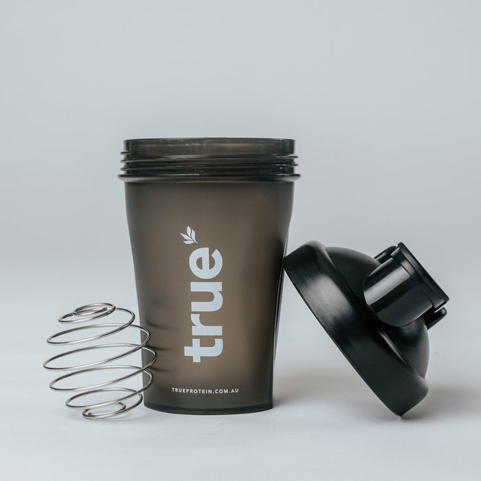 Black True Protein shaker bottle with stainless-steel mixing spring and black screw-on lid, white "true" logo and trueprotein.com.au (Australia)