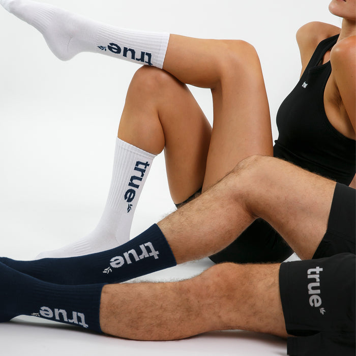 White and navy ribbed crew socks with "true" logo worn by male and female models — athletic cotton-blend crew socks product lifestyle shot
